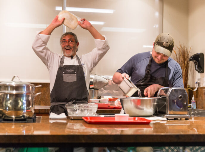 Man flips pizza dough in a playful Chef Events demonstration.
