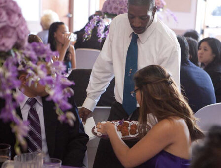 A woman grabs an hors d'oeuvres off of a serving platter at a Quinceaneras.