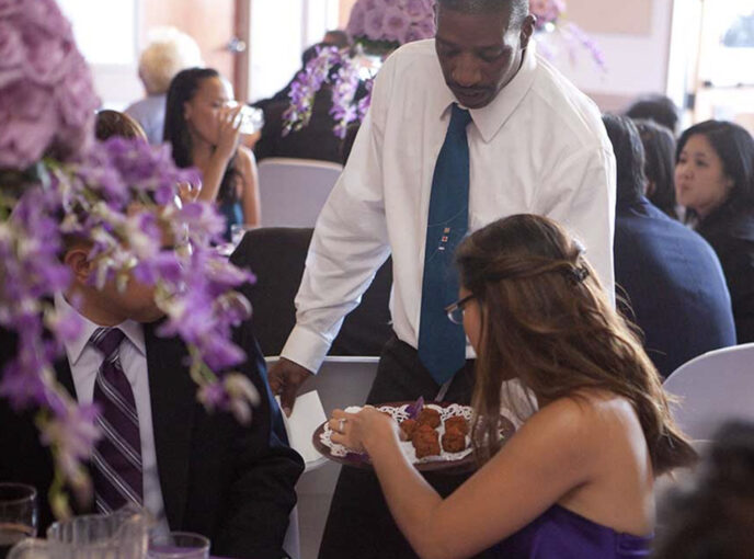 A woman grabs an hors d'oeuvres off of a serving platter at a Quinceaneras.