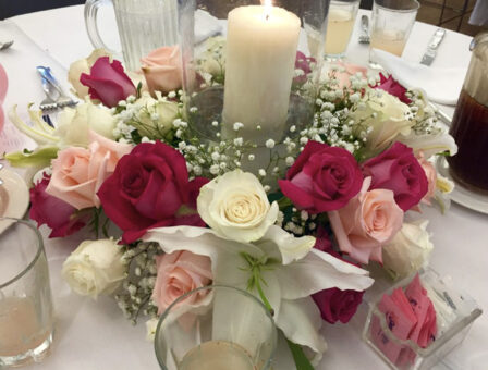 A rose and candle display on a table for a memorial service.