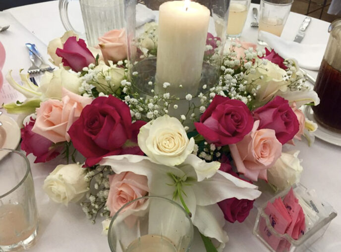 A rose and candle display on a table for a memorial service.