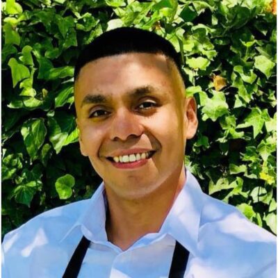 Man with short dark hair and white shirt smiles at camera