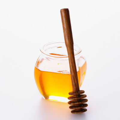 Jar of honey with wooden stirrer leaning on it