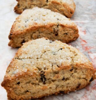 Three fresh raisin scones on a marble counter