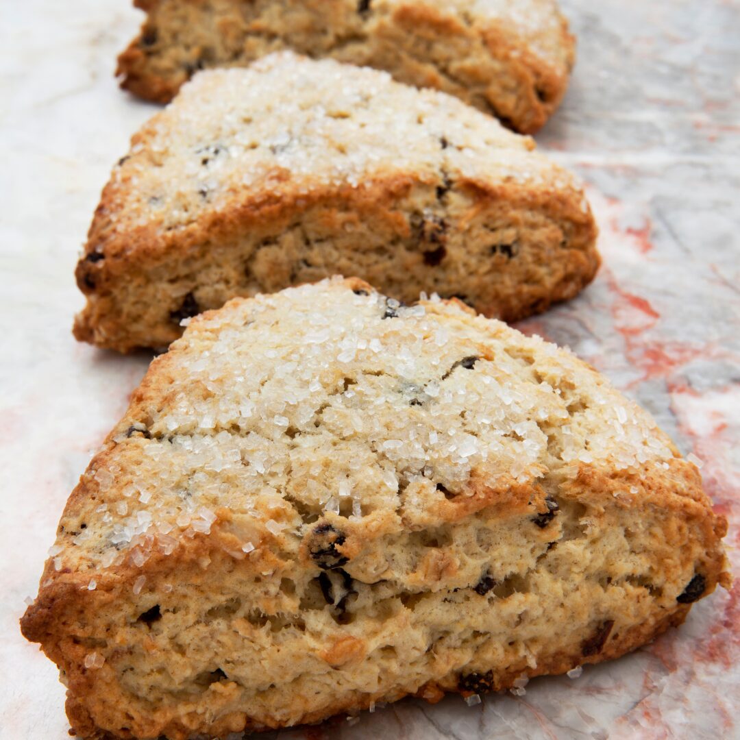 Three fresh raisin scones on a marble counter