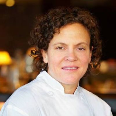 Woman with curly dark hair and white chef coat