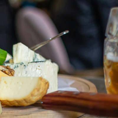 Plate of assorted cheese next to mug of beer