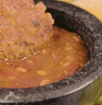 Black molcajete with red Mole sauce