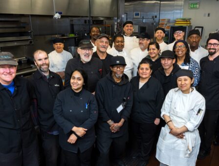 Culinary employees gather around a kitchen island