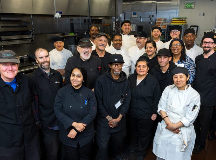 Culinary employees gather around a kitchen island