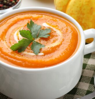 Hearty pumpkin soup in white cup with parsley garnish on top