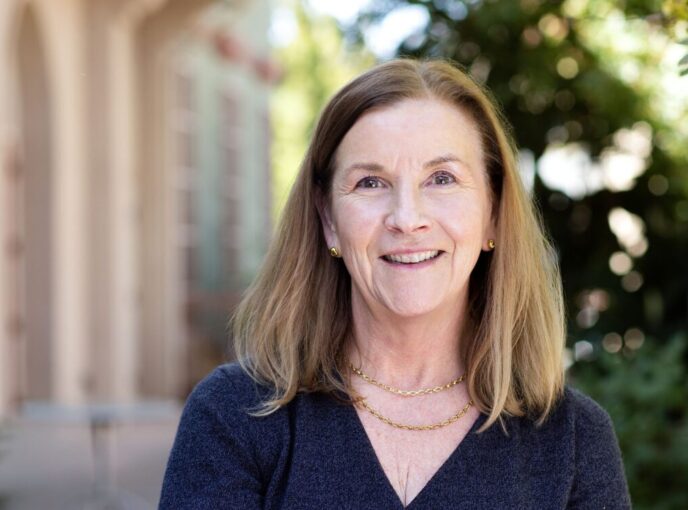 Woman with light brown hair and blue shirt smiles at the camera