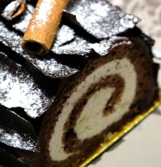 Decorated buche de noel cake with slice from the end to show the filling
