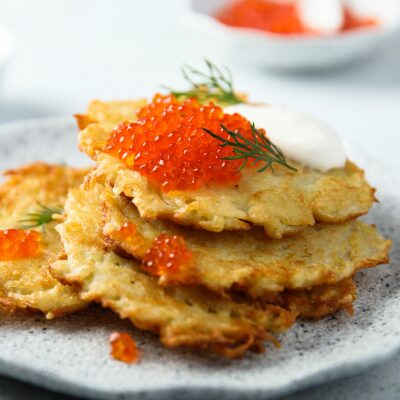 Golden latkes on a plate topped by caviar and dill