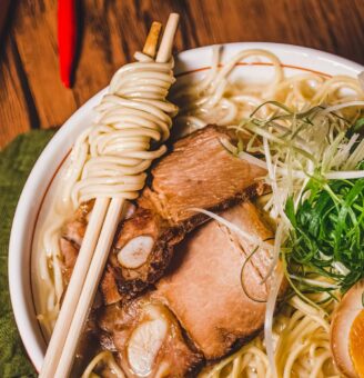 White bowl filled with ramen, pork and vegetables