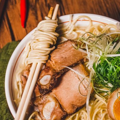 White bowl filled with ramen, pork and vegetables