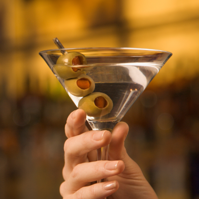 Woman's hand holding martini glass with olives