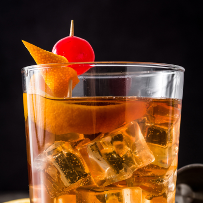 Old Fashioned cocktail in glass with ice and cherry