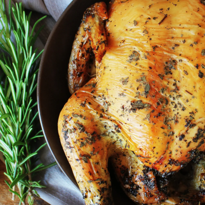 Plump roast chicken in a pan with rosemary